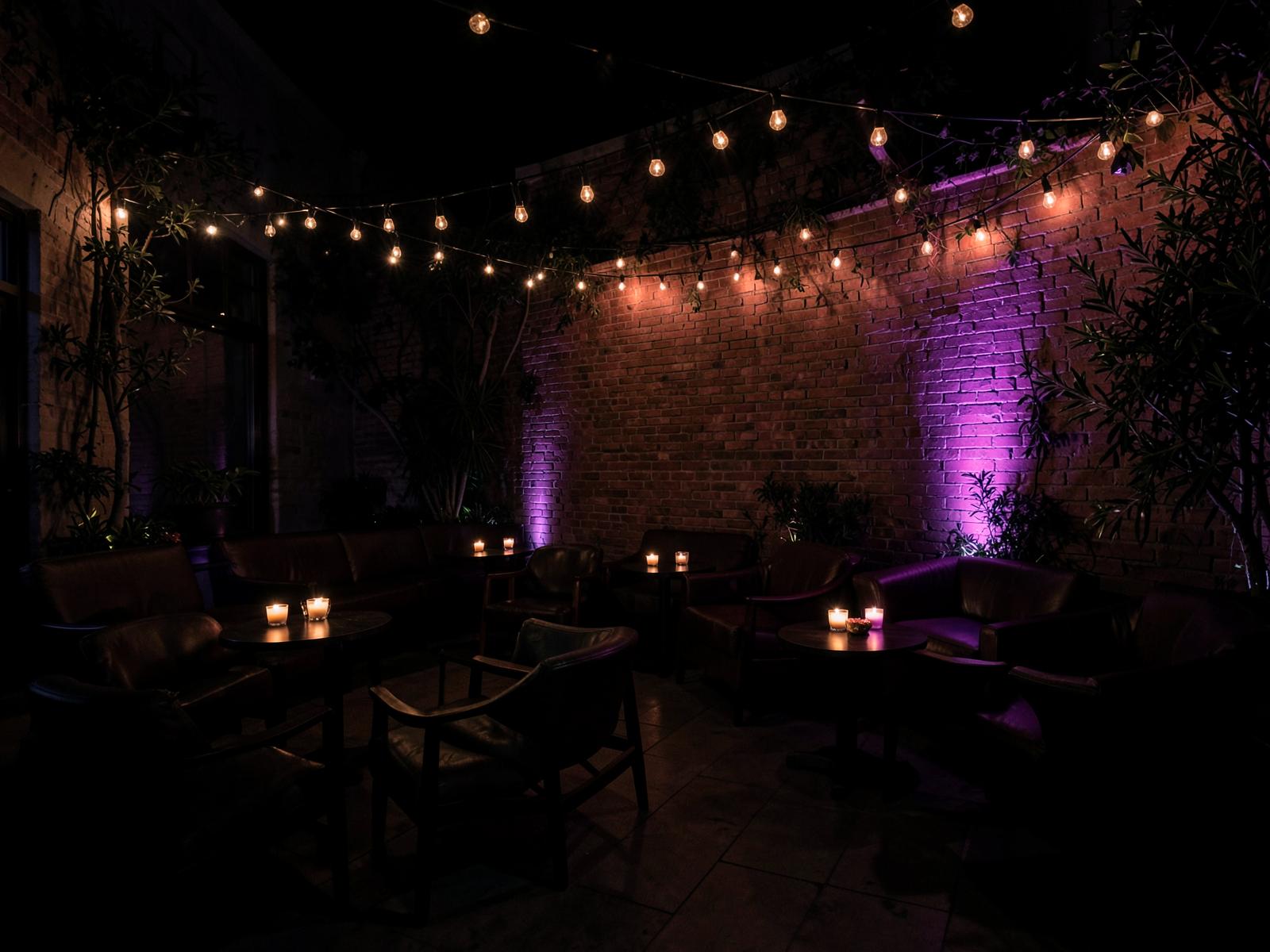 The outdoor patio at Pisco Gastrolounge at night, with string lights and candlelit lounge seating